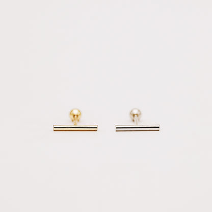 Minimalist bar earring worn on lobe piercing close up
