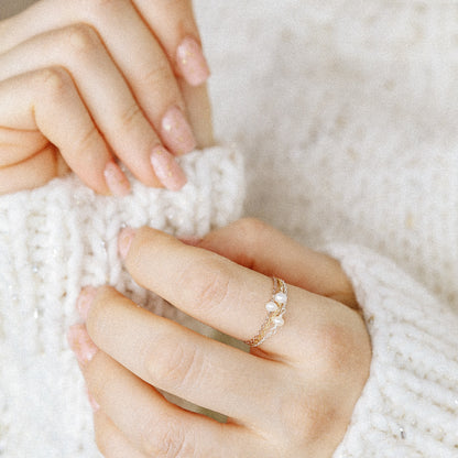 Close up of delicate pearl chain rings stacked on finger