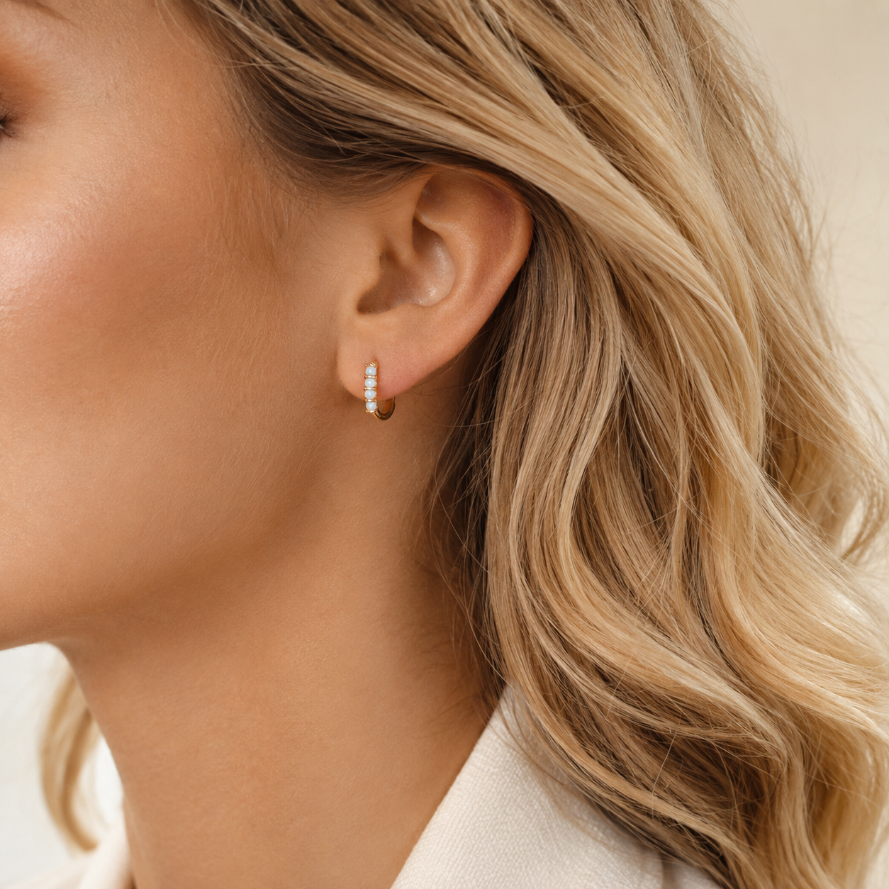Small gold opal huggie hoop earrings worn for an everyday minimal look