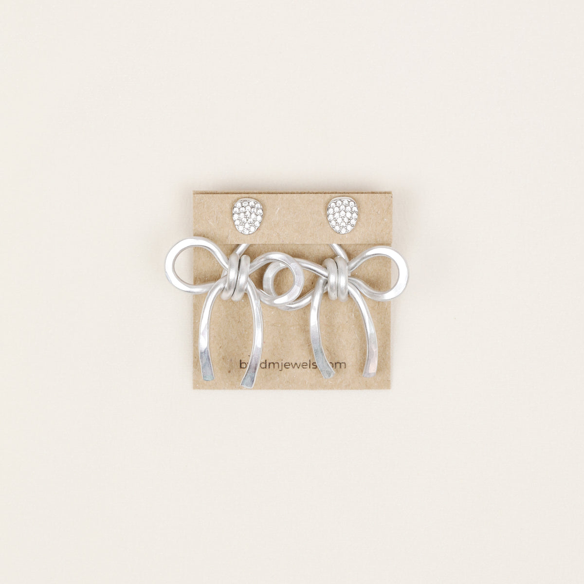Pair of silver medium bow ear jackets displayed on a jewelry card with stud earrings, showing the full matching pair option.