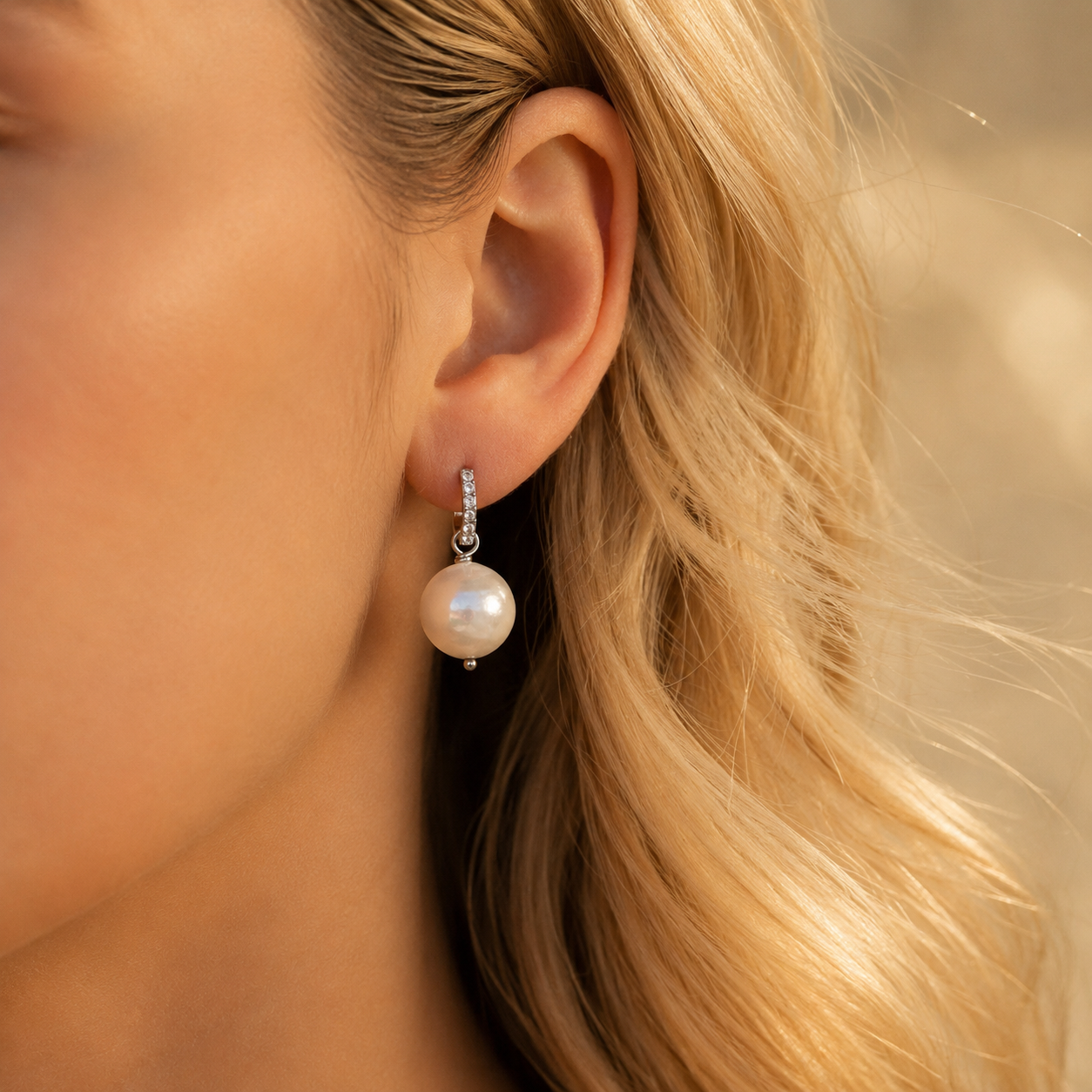 Pearl drop hoop earring worn on blonde model in warm golden light with elegant dangle design