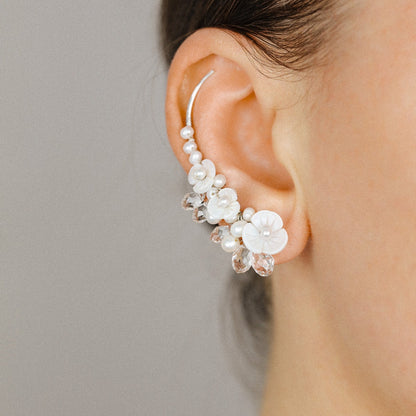 Close up of floral pearl ear climbers following the curve of the ear
