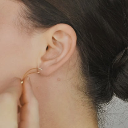 Video tutorial showing how to wear a handmade ear climber through a standard lobe piercing, inserting the wire like a regular earring and rotating it upward along the ear curve, with matching no-piercing upper helix cuffs styled above for a minimalist layered ear stack.