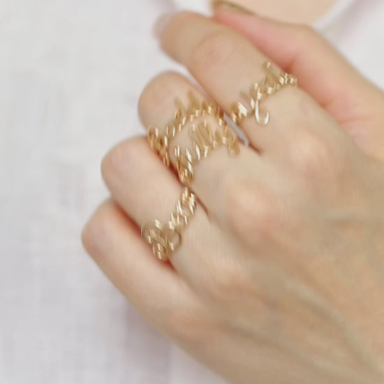 Stacking look featuring multiple handmade gold name rings like "Sully", "Yeah", "Bear", and "Buddy".