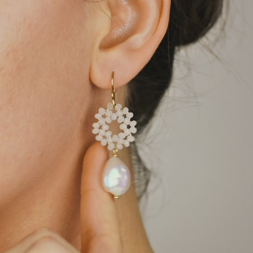 Close-up of a woman wearing a gold-plated baroque pearl drop earring with a delicate white crystal wreath, showcasing its elegant bohemian style.