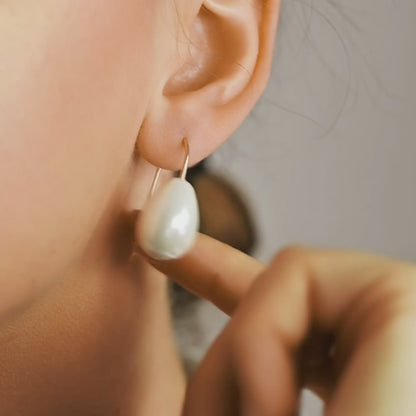 Handmade ceramic pearl teardrop earrings featuring large white pear-shaped pearls approximately 20 mm x 15 mm suspended from a minimalist curved wire hook, approximately 30 mm total length, available in solid 925 sterling silver, 14k gold filled or 14k rose gold filled.