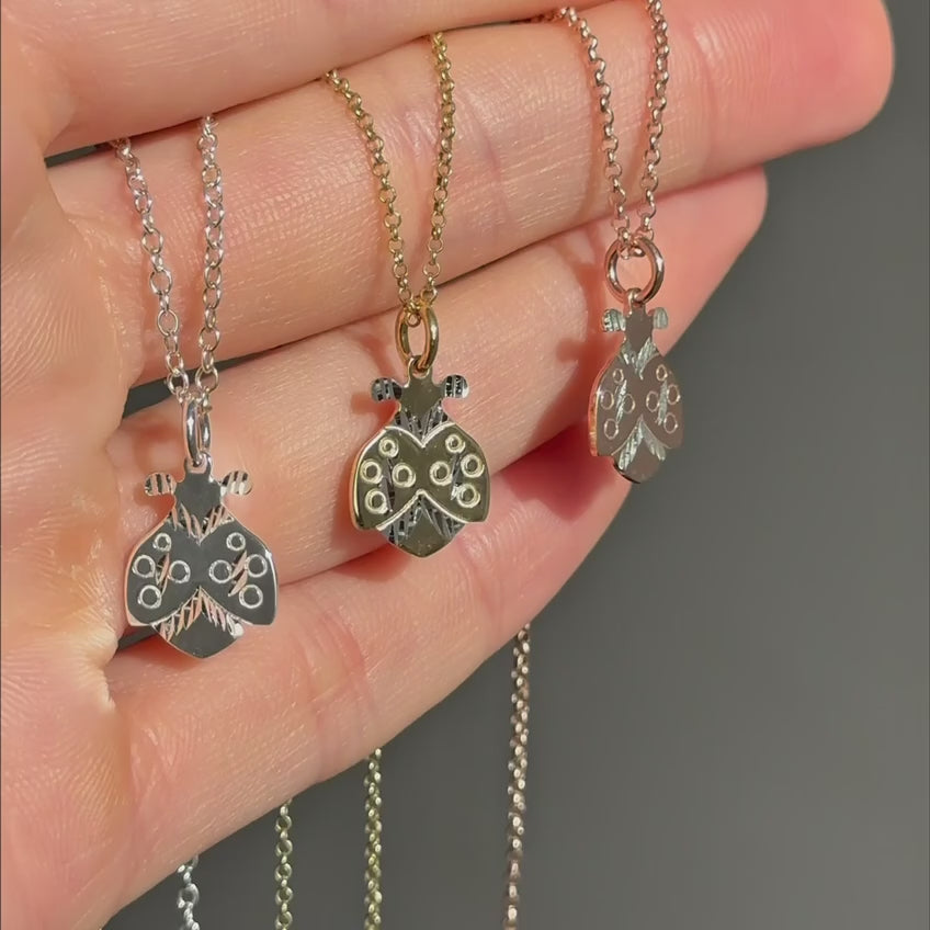 Ladybug pendant necklaces displayed in silver gold and rose gold on neutral textured background