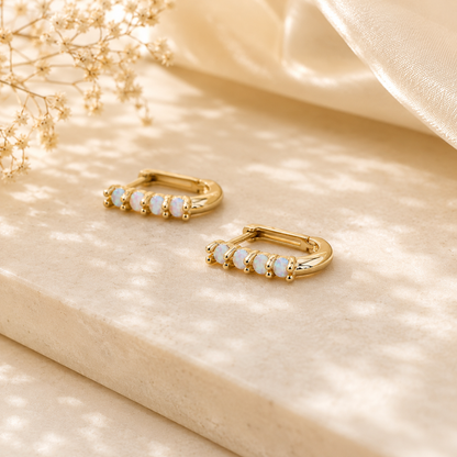 Gold rectangular huggie earrings with opal stones shown upright on a light background