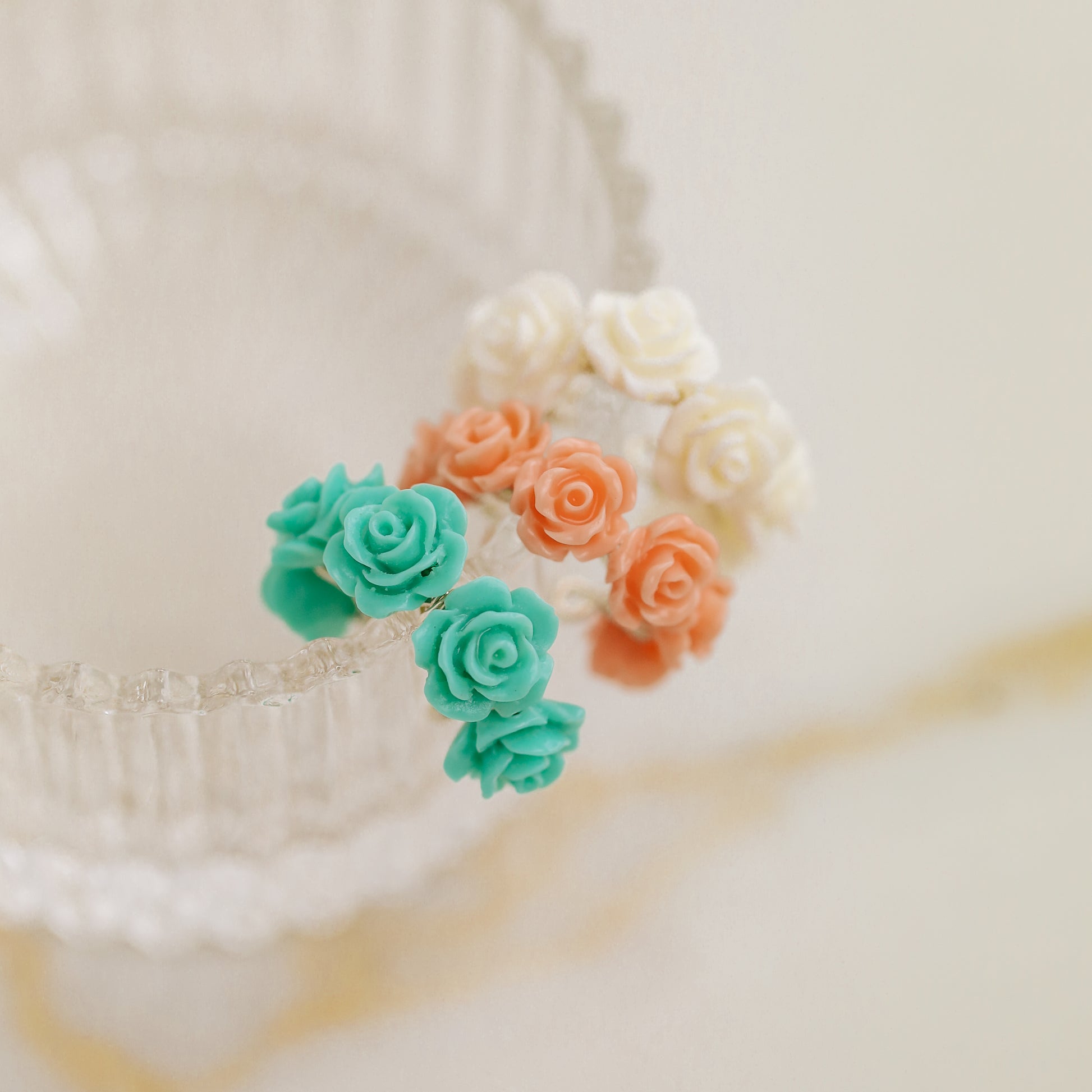 Floral resin rose conch ear cuffs displayed on a gold jewelry stand in white ivory, turquoise aqua blue and peach coral colors
