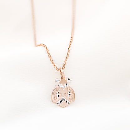 Rose gold ladybug necklace close up on soft white fabric background