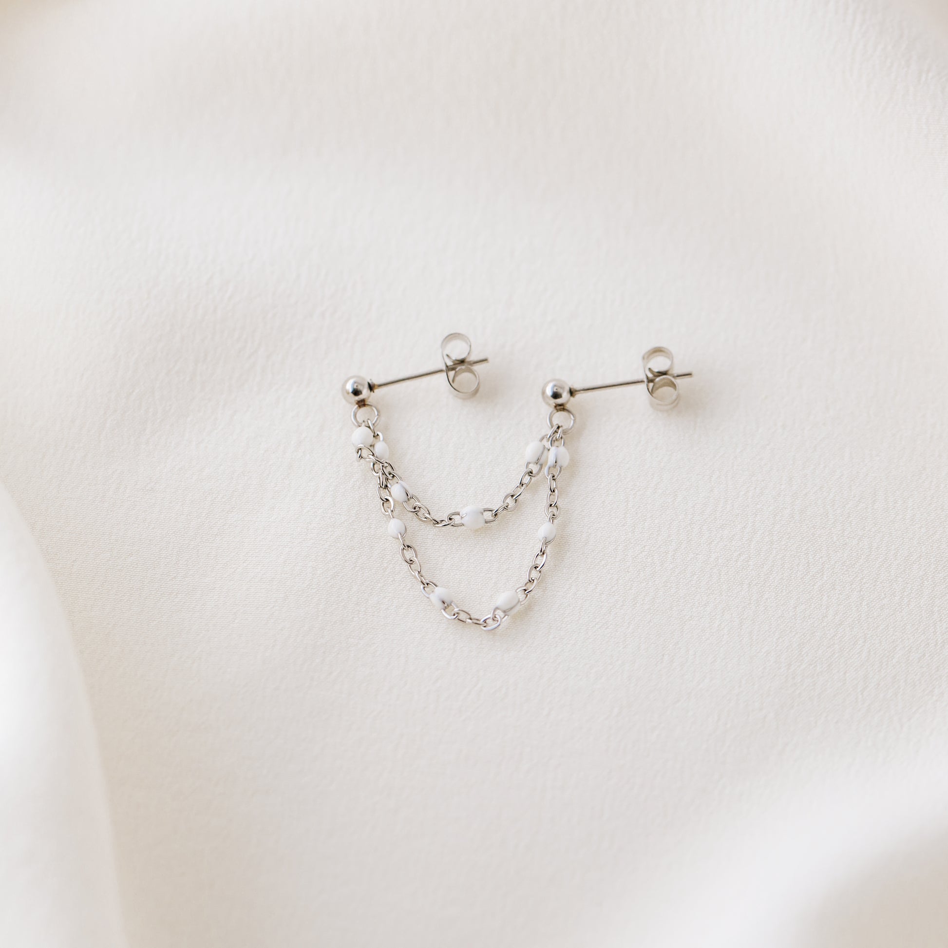 Silver double chain stud earring displayed on white fabric with push back closure