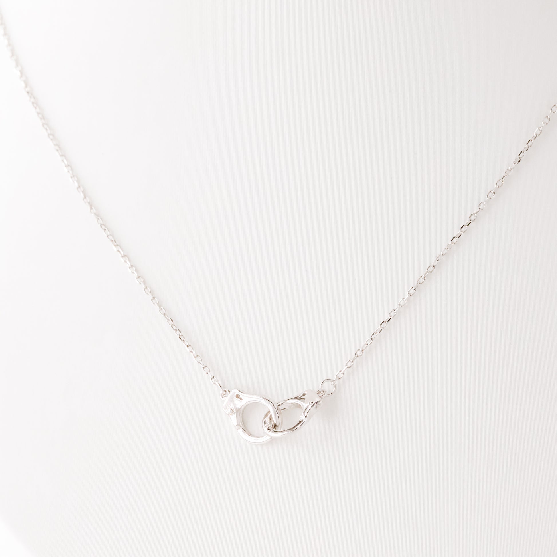Close up detail of sterling silver handcuff pendant necklace on delicate chain