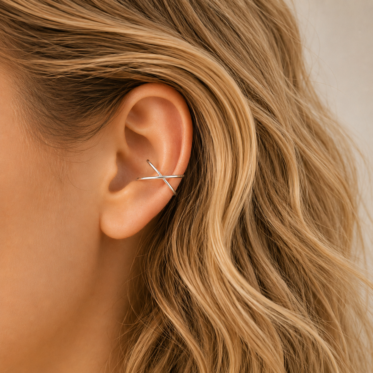 Silver smooth criss cross ear cuff worn on the upper ear, designed as a minimal no piercing ear wrap.