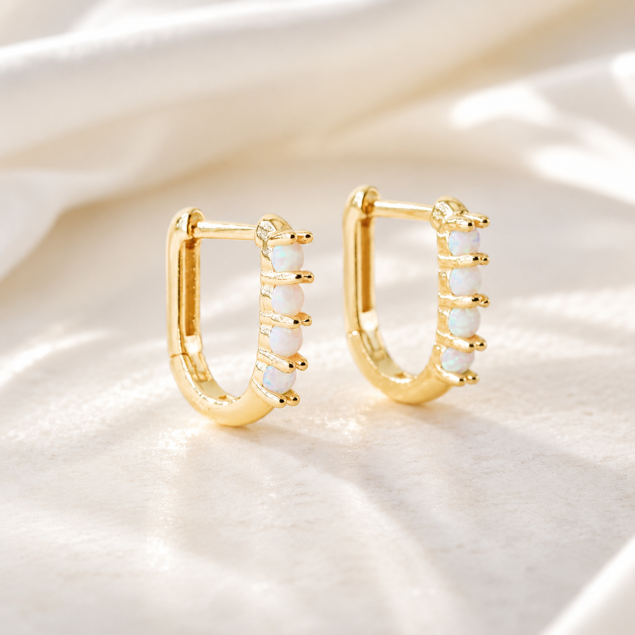 Small gold opal huggie hoop earrings worn for an everyday minimal look
