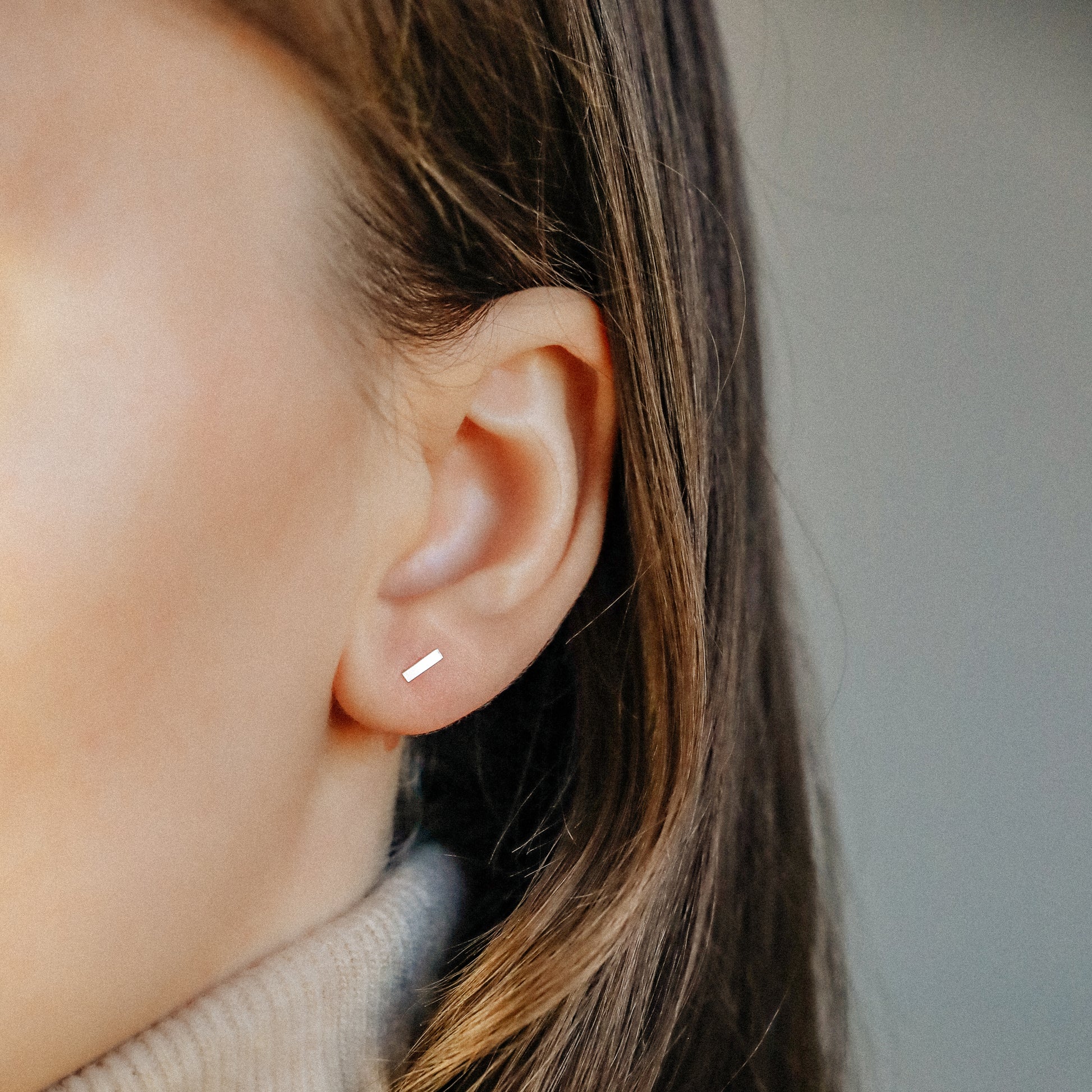 Minimal rectangle bar stud earring worn on ear close up