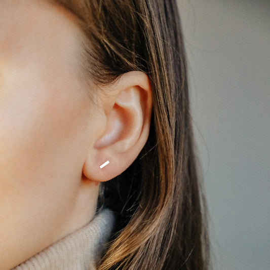 Minimal rectangle bar stud earring worn on ear close up