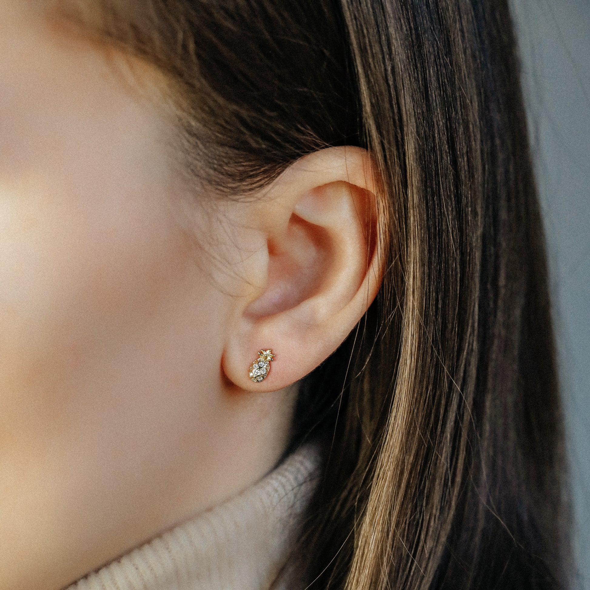 Tiny pineapple stud earrings worn on ear in 18k gold plated sterling silver