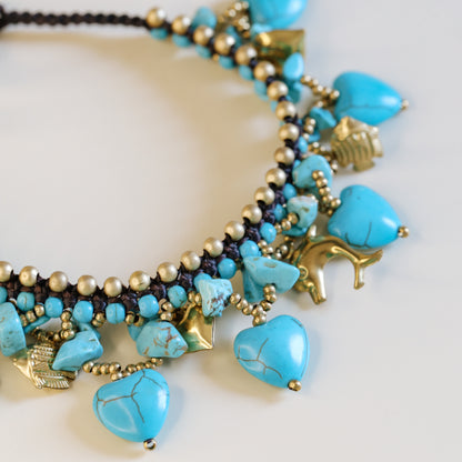 Close-up of the brown waxed cord and adjustable loop closure with small gold-tone bells on the turquoise anklet.