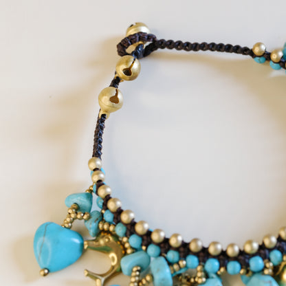 Close-up of the brown waxed cord and adjustable loop closure with small gold-tone bells on the turquoise anklet.