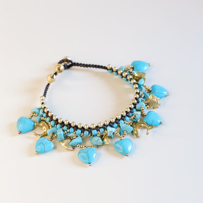 Close-up of the brown waxed cord and adjustable loop closure with small gold-tone bells on the turquoise anklet.