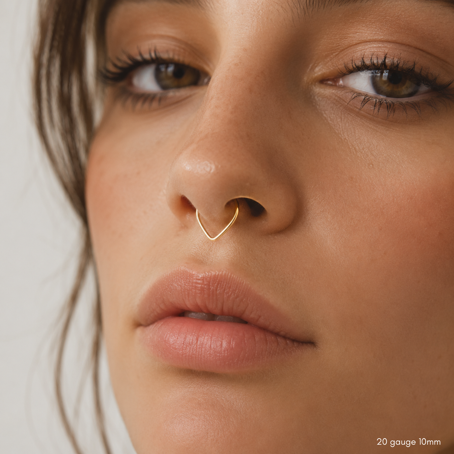 Close-up model photo featuring a delicate V-shaped gold septum hoop.